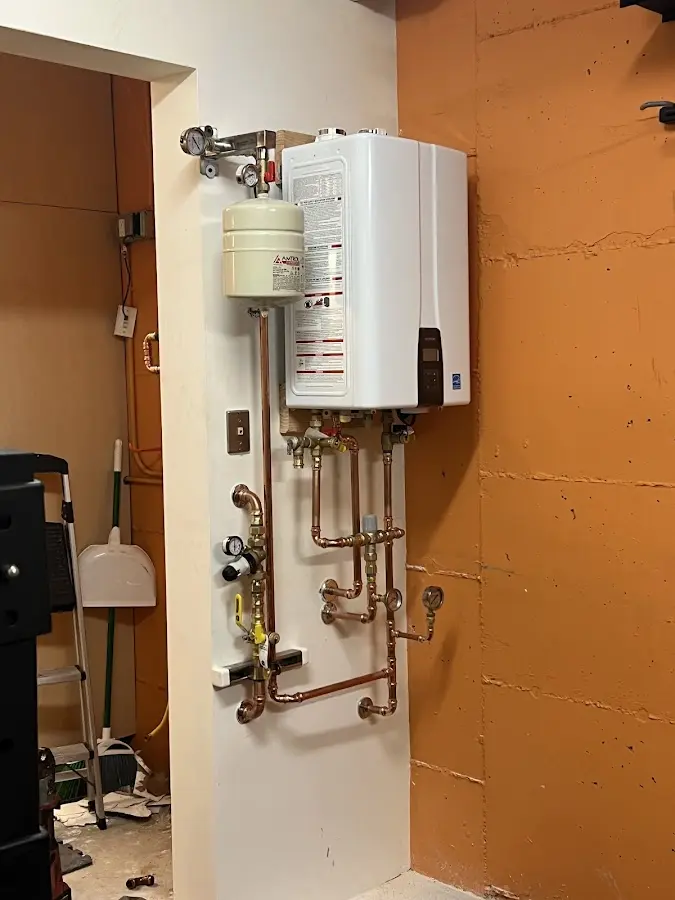 Plumbing technician inspecting water heater connections in Keene